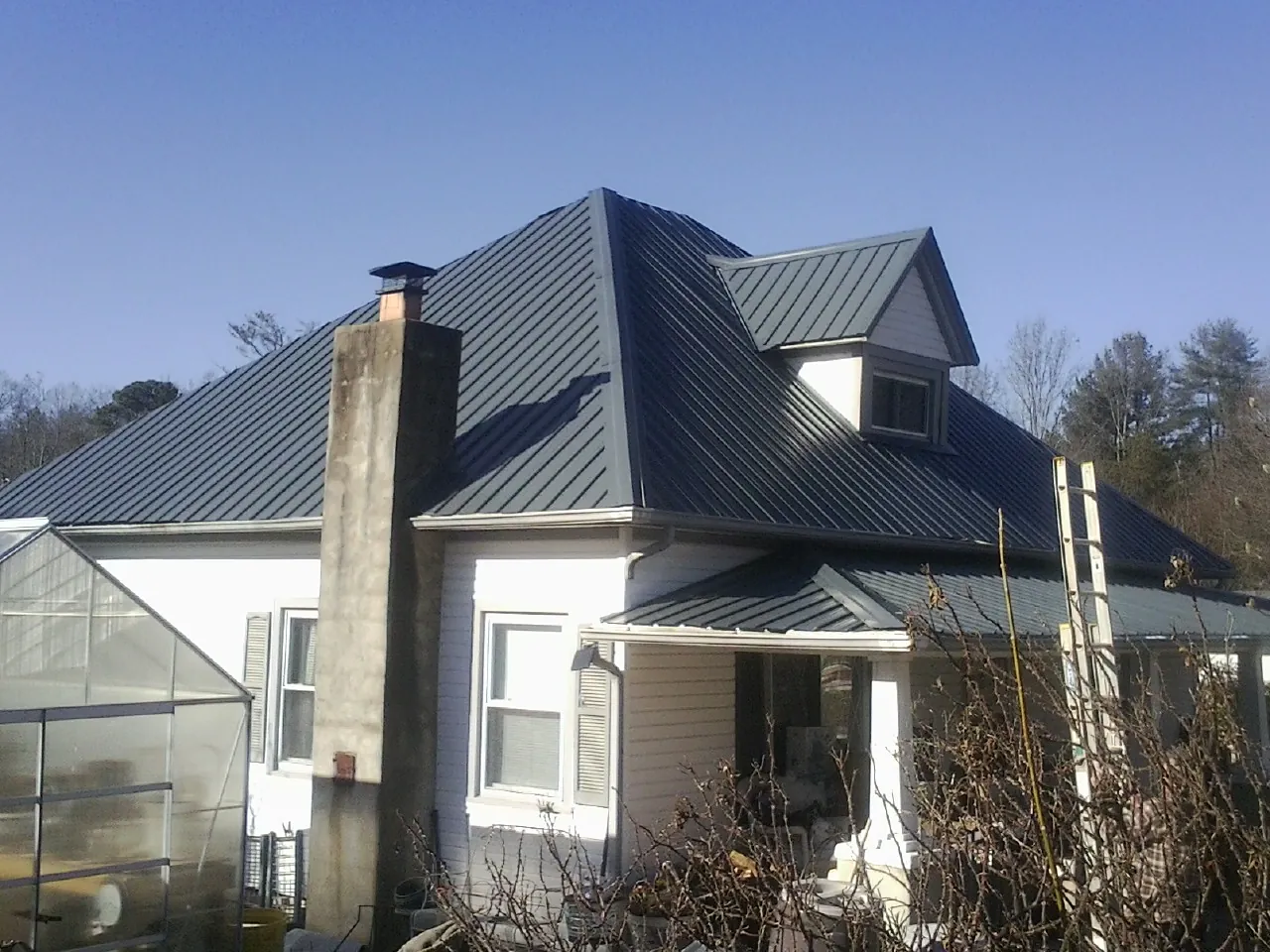 Dark blue standing seam metal roof on a white farmhouse with dormer — Slate & Tile Roof Repair by Roofing Brothers in Glencliff