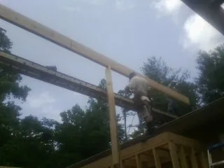 Carpenter setting a ridge beam over a new addition frame — Ice Dam Removal by Roofing Brothers in Glencliff