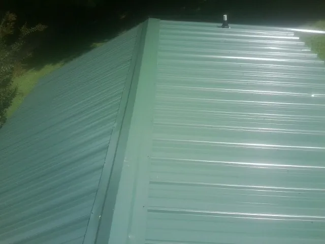 New green metal panels meeting at the ridge of a roof — Flat Roof Repair work by our crew in Glencliff