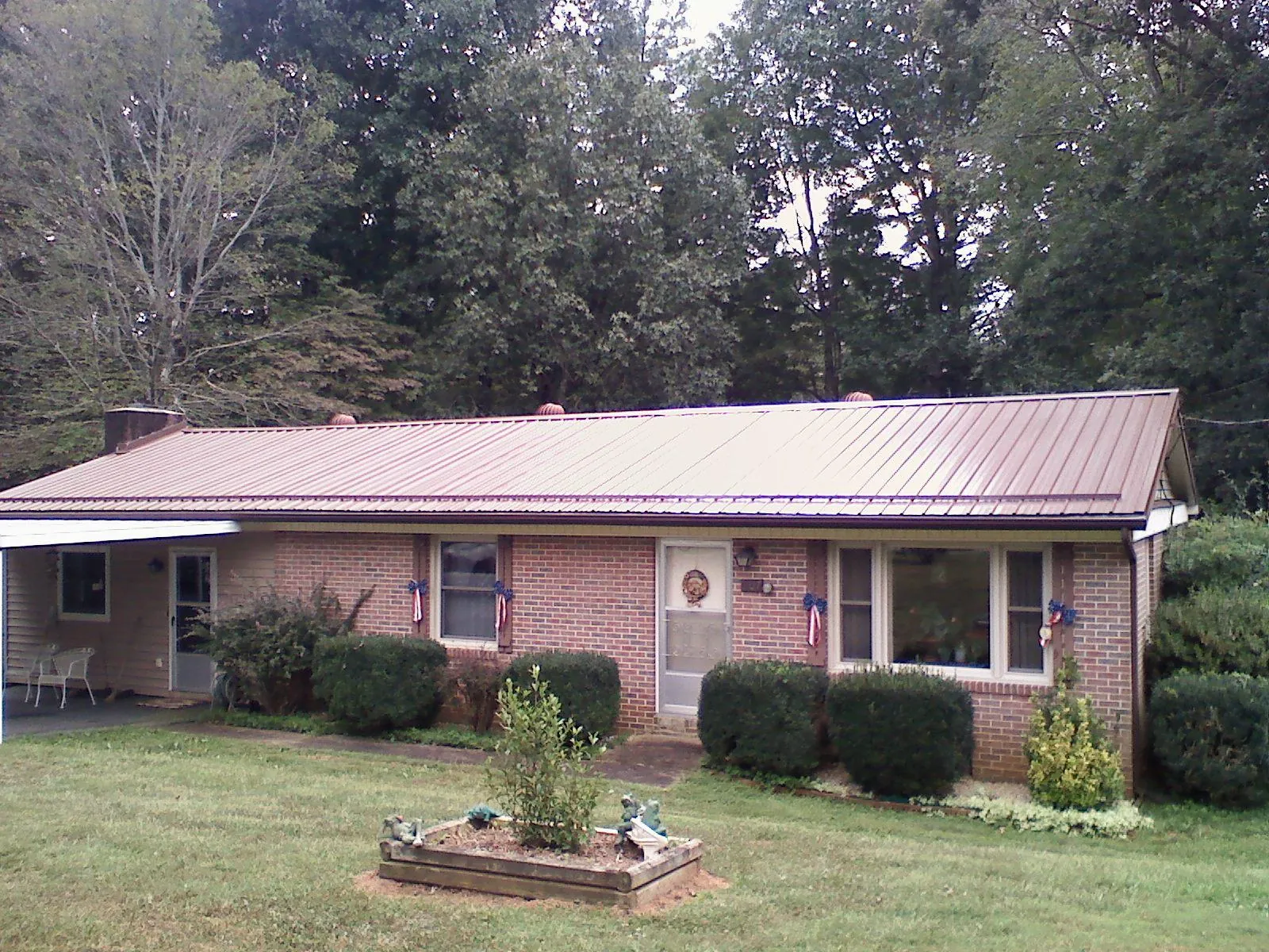 Bronze metal roof on a brick ranch home with a carport in Glencliff