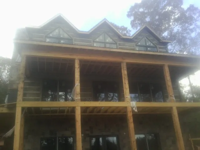 Dormers and porch framing on a large log home under construction — Roof Coating work by our crew in Glencliff