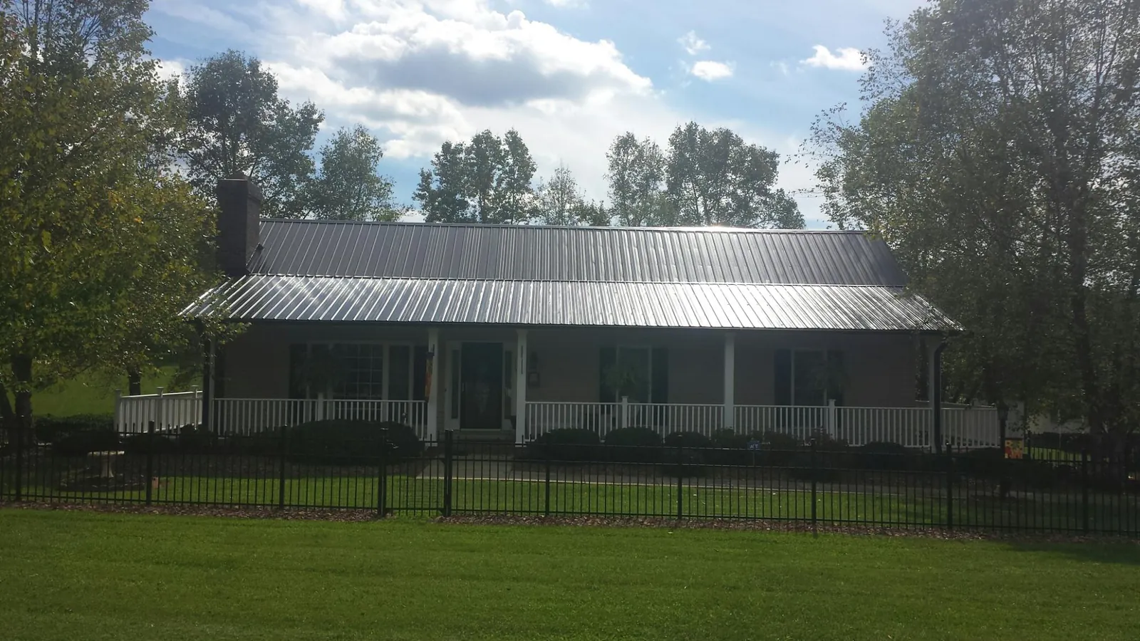 Gray metal roof on a brick ranch with a full width front porch — Gutter Guard Installation work by our crew in Glencliff