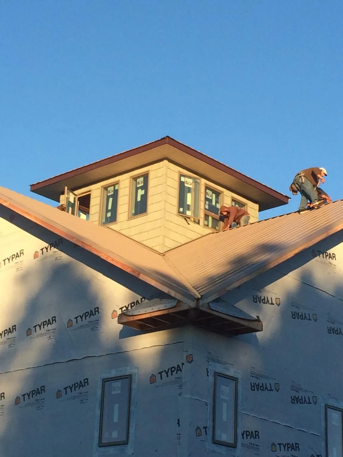 Roofers working around a rooftop cupola on a new metal roof at sunset — Roof Waterproofing in Glencliff by Roofing Brothers